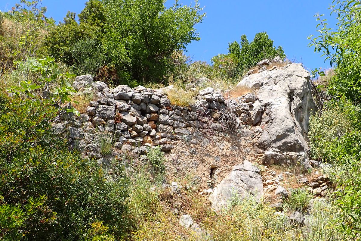 wall remains at the NE side, above the church of Taxiarches